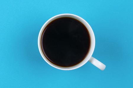 Black coffee in white cup on blue blackground pastel style copyspace flatlay.の写真素材