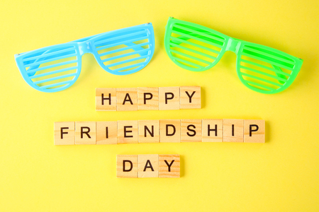 The concept for the international friendship day. Text and glasses on a yellow pastel backgroundの写真素材