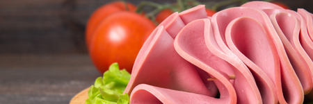 Sliced sausages with salad leaves on the wood background.の写真素材