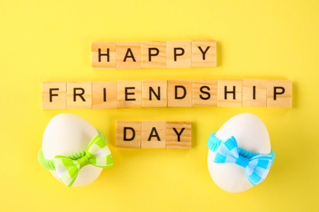 The concept for the international friendship day. Text and eggs in bows on a yellow pastel backgroundの写真素材