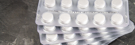 Blisters of white pills on a gray concrete background.
