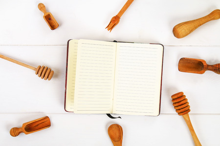 Notebook and wooden utensil in kitchen on white wooden background with copy space
