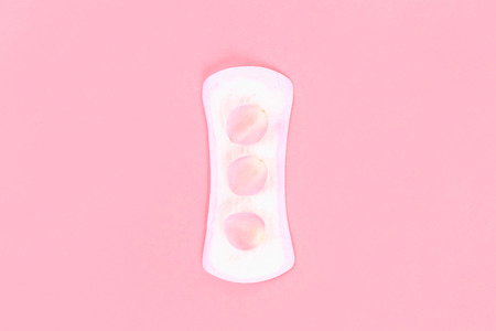 Daily sanitary pads on a pink pastel background with rose petals. The concept of ease, security, femininityの写真素材