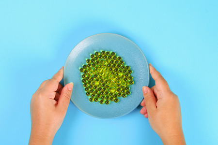 Plate with capsules of fish oil on a blue table background. Top view, copy space, flat lay
