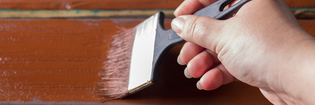 Brush with paint in hand. A man paints blue boards in a brown paint brush.の写真素材