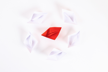 Red paper boat among other white. Leadership, white crow, individuality. Piranhas and a shark. Not like everyone else. Origami. Top view, flat lay, copy spaceの写真素材