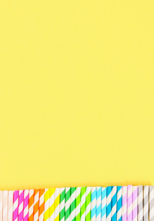 Multi-colored straw paper tubes on a bright yellow pastel background. Top view, copy spaceの写真素材