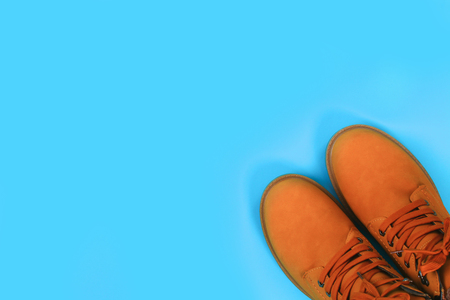 Orange brown mens autumn boots on a blue pastel background. Top view, copy spaceの写真素材