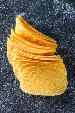 A stack of crispy chips on a gray dark table. Snackの写真素材