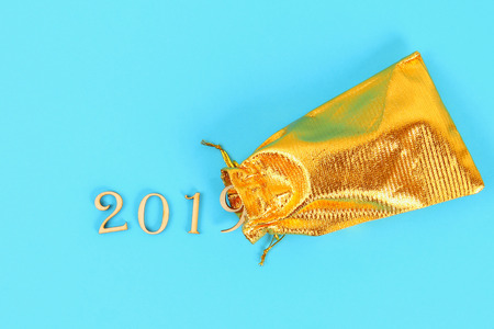 The text of the year 2019 falls from a golden bag on a blue background. Top view, flat layの写真素材