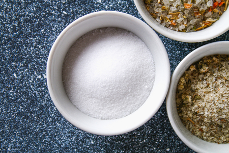 Different types of salt in glass bowls on a dark gray tableの写真素材