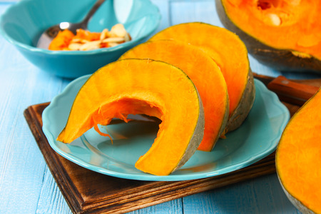 Sliced pumpkin into pieces for cooking pumpkin soup or mashed potatoes. Pumpkin on a blue wooden tableの写真素材