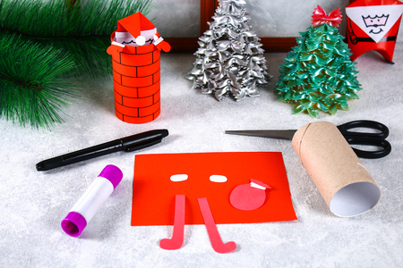 Christmas Santa Claus in chimney made from toilet paper hub, colored paper, marker, glue, fishing line and cotton pad. DIY toy on the Christmas tree. Handmade Guide, step by step. Christmas decorの写真素材