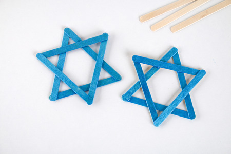 DIY. Hanukkah decor. Star of David from ice cream sticks on a white wooden table. Guide, step by...