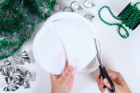 Diy Christmas wreath. Guide on the photo how to make a Christmas wreath with your own hands from a plastic plate, tinsel, beads, bows and balls. Handmade The decor. Silver green wreath. Top viewの写真素材