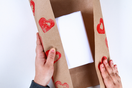 Diy. Gift wrapping for Valentine's Day. Kraft paper gift and potato stamp in the shape heart and red paint do it yourself on February 14th. Top view on a white background. step by step. Handicraftの写真素材