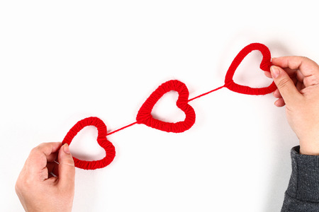 Red handmade diy hearts made of cardboard, yarn on a white background. Gift ideas for Valentines...