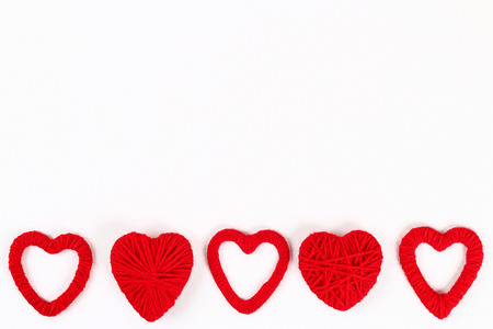 Valentine day layout. Red homemade diy hearts made of cardboard and yarn on a white background. Idea...