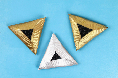 Purim. Diy cookies hamantaschen of cardboard plates with sweet surprise inside on blue background....