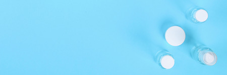 Banner. Set of empty small traveling cosmetics bottles on blue background. For soap, shampoo, shower...