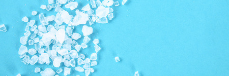 Crystals of large sea salt and dill on a blue tableの写真素材