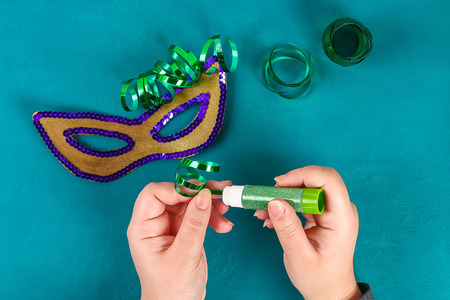 Diy Masquerade mask Mardi Gras, Fat Tuesday. Gift idea, decor Mardi Gras. Carnival mask cardboard, sequins, paper, beads. Step by step. process childrens crafts. Top view. Green yellow purpleの写真素材