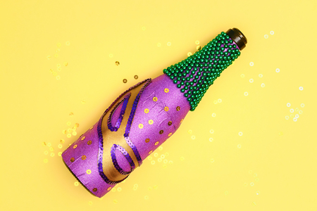 Diy Mardi Gras bottle purple self adhesive paper, green bead, carnival mask, sequins yellow background. Gift idea, decor Mardi Gras, Fat, Shrove Tuesday. Step by step. Top view. Process children craftの写真素材