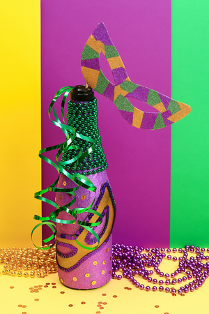 Diy Mardi Gras bottle purple self adhesive paper, green bead, carnival mask, sequins yellow background. Gift idea, decor Mardi Gras, Fat, Shrove Tuesday. Step by step. Top view. Process children craftの写真素材