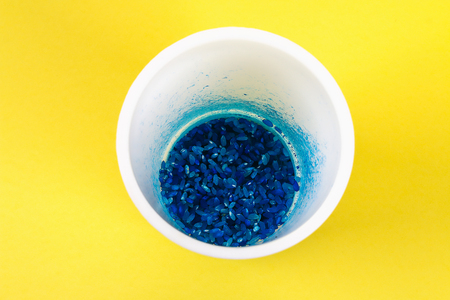 Diy Easter egg painted with colored rice on a yellow background. The decor of eggs for Easter. Gift idea, decor Spring, Easter. Step by step. Top view. Process kid children craft.の写真素材