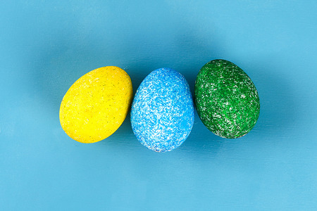 Diy Easter egg painted with colored rice on a blue background. The decor of eggs for Easter. Gift...