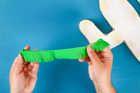 Diy cinco de mayo Mexican Pinata Cactus made cardboard and crepe paper your own hands on a blue background. Gift idea, decor, game cinco de mayo. Step by step. Top view. Process kid children craft.の写真素材
