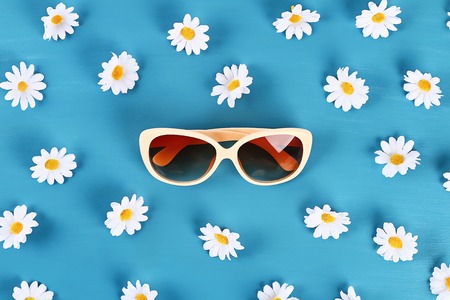 Sunglasses and daisies on a blue background. Top view. Summer background. Flat lay.の写真素材