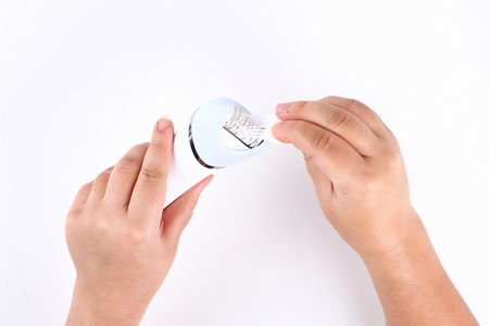 Girl brushes electric epilator brush on white background. Top view.の写真素材