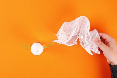 10 Diy Halloween ghost of starch and gauze on orange background. Gift idea, decor Halloween. Step by step. Top view. Process kid children Halloween craft. Workshop.の写真素材