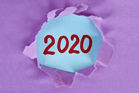 Torn piece paper revealing word new year 2020. Christmas. Business, finance, salary, crisis, and...