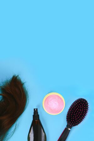 Hair, hair mask, comb, spray on a pastel blue background. The concept of hair care. Copy space, top viewの写真素材