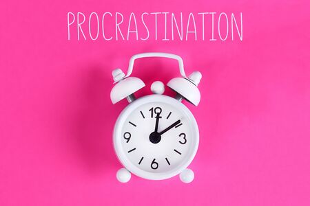 Procrastination, delay and urgency concept. White alarm clock with text procrastination.の写真素材