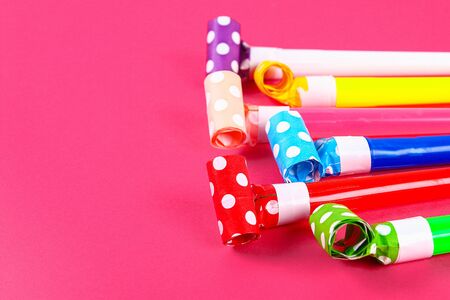 Multicolor party blowers on pink background. Multicolored party whistles. Decor for birthday.の写真素材