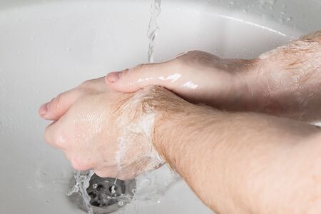 Man use soap and washing hands under water tap. Hygiene concept hand detail.の写真素材
