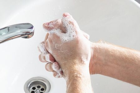 Man use soap and washing hands under water tap. Hygiene concept hand detail.の写真素材