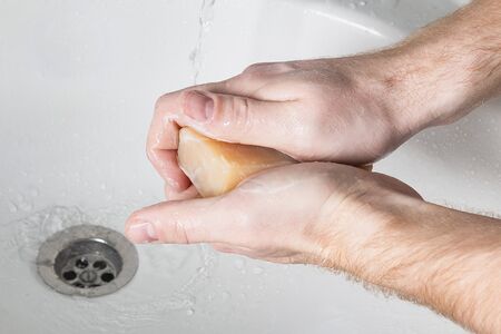 Man use soap and washing hands under water tap. Hygiene concept hand detail.