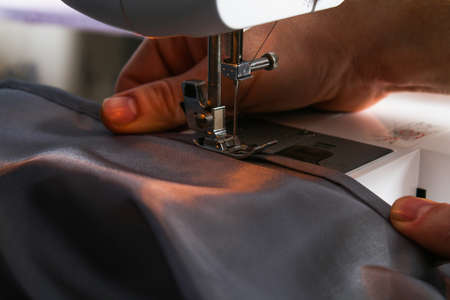 A man hem a curtain on sewing machine. Sewing, hobbies, hobby, home improvement.