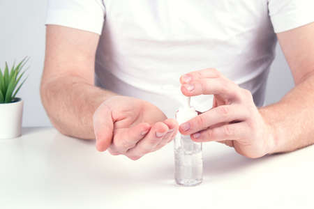 Man person using small portable antibacterial hand sanitizer on the hands.