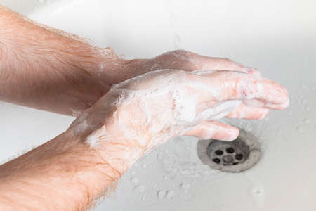 Man use soap and washing hands under water tap. Hygiene concept hand detail.
