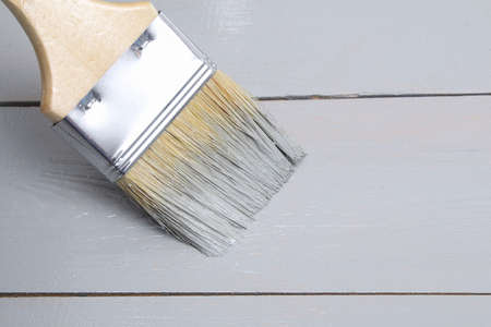Brush with can paint in hand. A man paints wooden boards in a gray paint brush.の写真素材