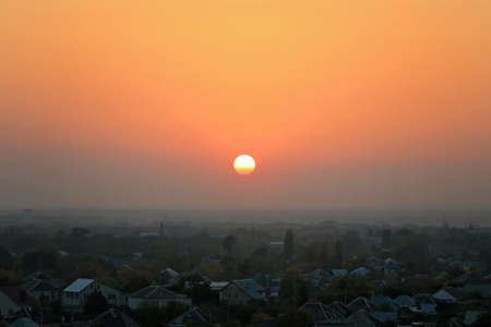 Sunset over the foggy city, houses. City during warm sunsetの写真素材