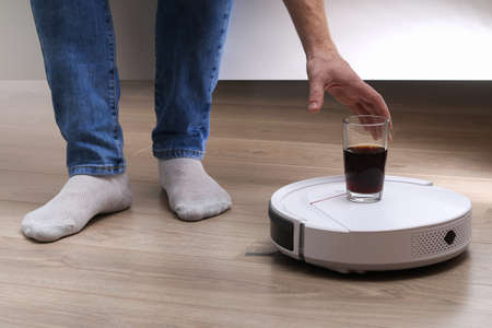 A robot vacuum cleaner brought a drink in a glass.