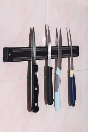A man takes a knife from a magnetic kitchen holder for knives, scissors, metal tools.