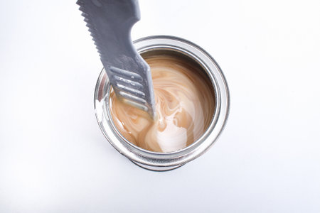 A man stirring white paint in a can on a white background. Renovation concept.の写真素材
