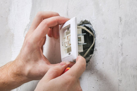 A worker removes the light switch for wallpapering.の写真素材